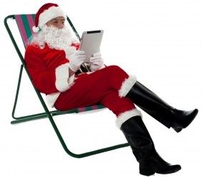 Kris Kringle Relaxing And Using Electronic Tablet by stockimages courtesy of freedigitalphotos.net